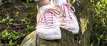 Jugendliche in rosa Sprotschuhen balanciert auf einem Stamm.