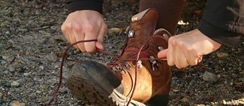 Jugendlicher bindet einen Wanderschuh.