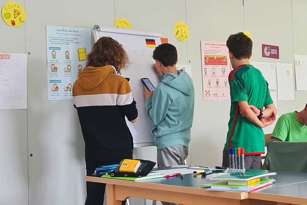 Jugendliche stehen an einer Magnettafel und schreiben.