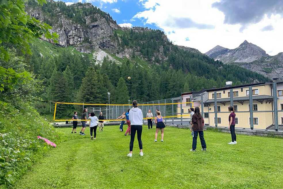 Jugendliche spielen Volleyball auf einer Wiese.