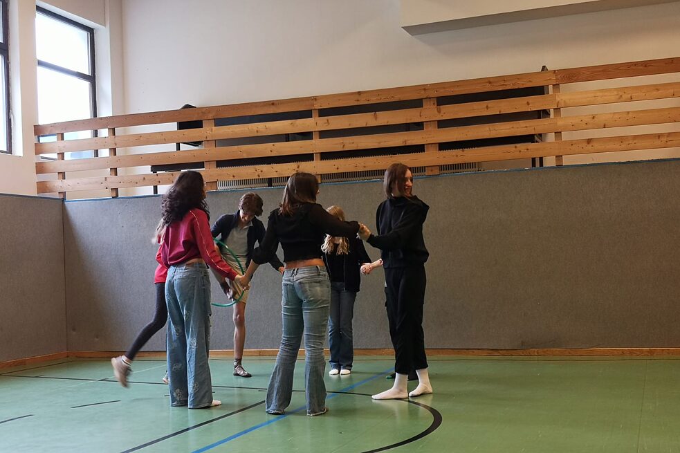 Jugendliche stehen zusammen in einer Turnhalle