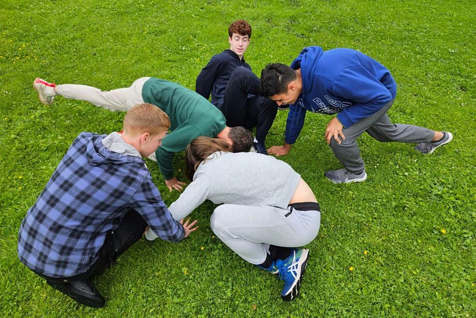 Fünf Jungs raufen auf dem Rasen.