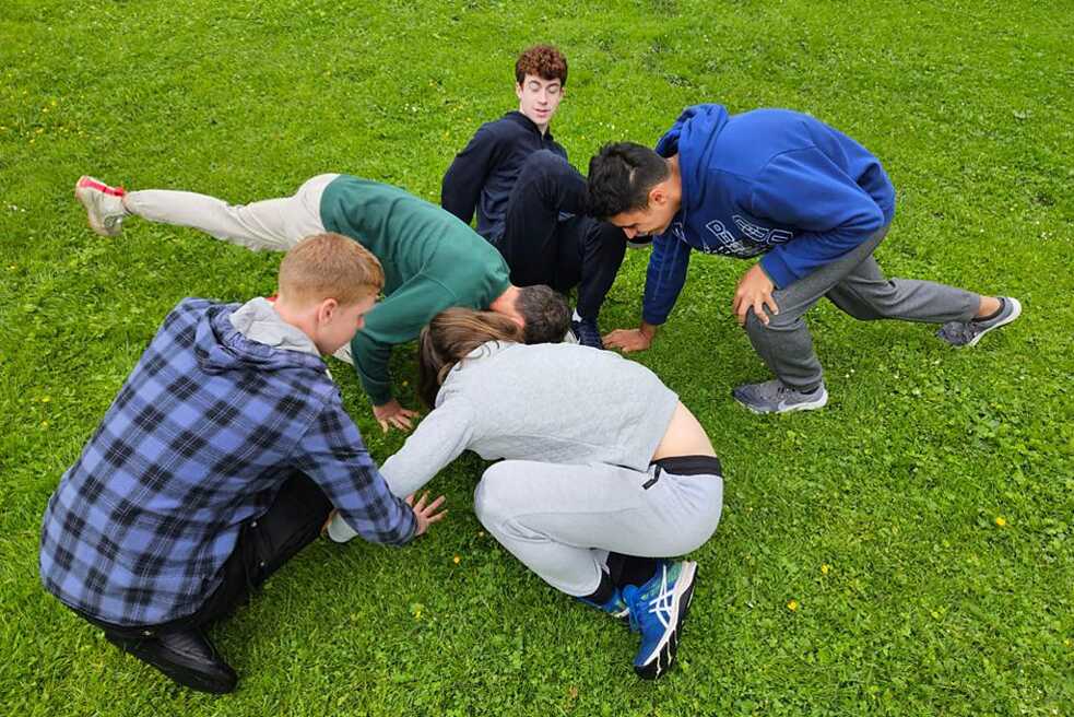 Fünf Jungs raufen auf dem Rasen.