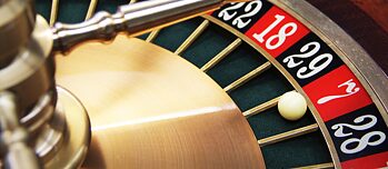 Fotoausschnitt eines Roulettekessels, darin liegt eine weiße Kugel auf der Zahl „7“.