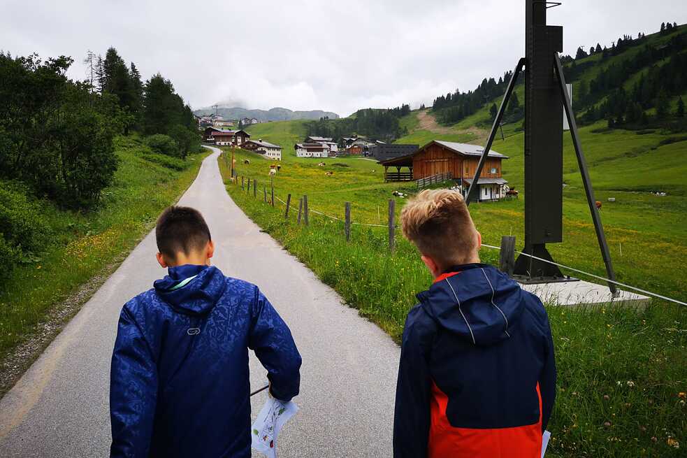 Zwei Jungs auf einem gefestigten Weg in den Bergen. Einer davon hält eine Karte in der Hand.