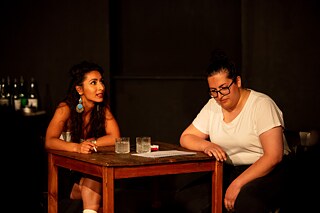 Torkan Omari (left) and Mina Jawad (right) are sitting together at a table with two glasses on it. The two people are engrossed in a conversation.