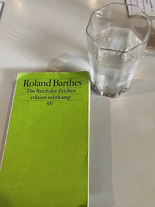 Geschlossenes Buch mit der Aufschrift „Roland Barthes – Im Reich der Zeichen“, daneben ein Glas mit einer klaren Flüssigkeit