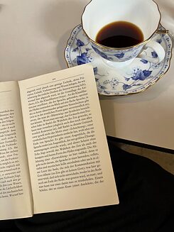 Open book, next to it a cup with coffee