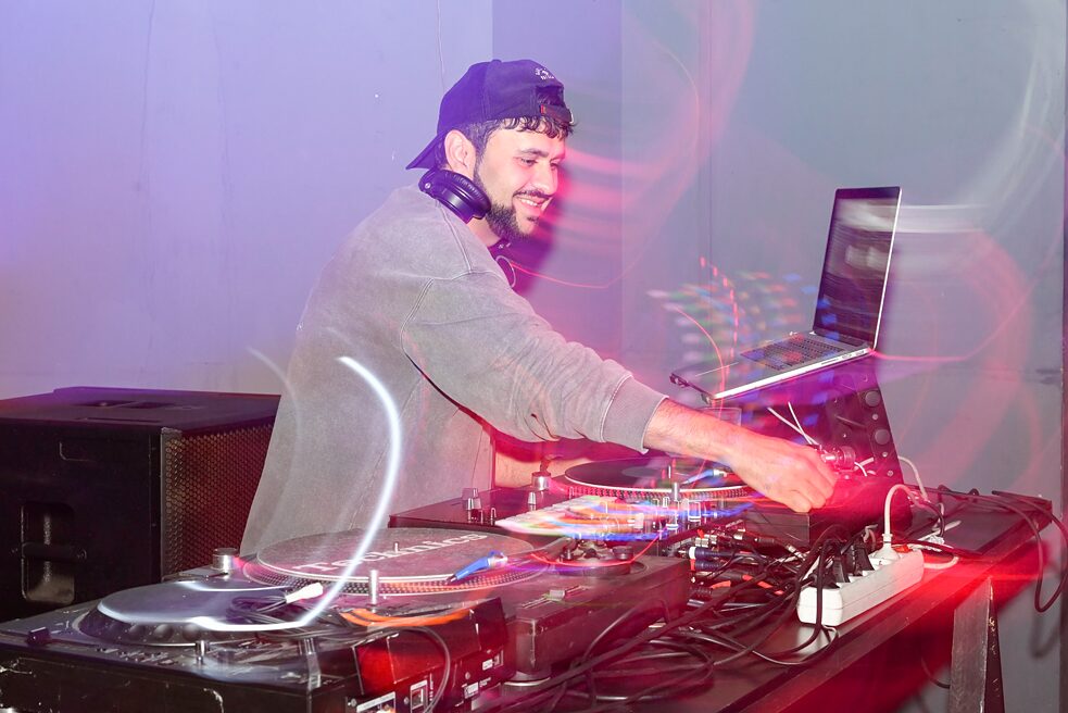 Das Foto zeigt den lächelnden Musikproduzenten Farhot an seinem DJ-Pult.