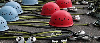 Gurte und Helme liegen aufgereiht auf dem Boden