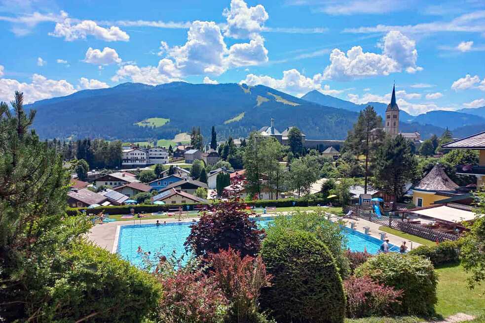 Ein Blick auf das Freibad Radstadt, im Hintergrund sieht man Häuser, einen Kirchturm und Berge.