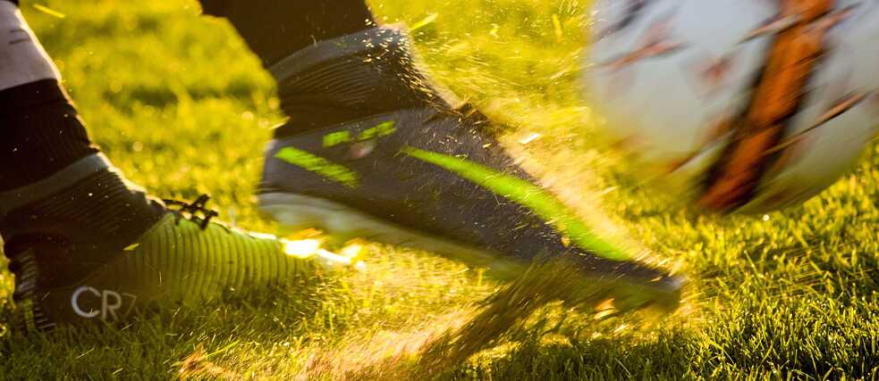 Nahaufnahme Fußballschuhe, die einen Ball treten.