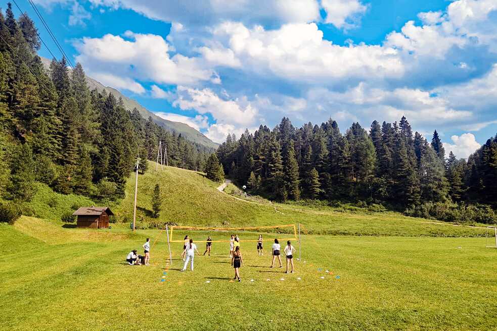 Jugendliche spielen Volleyball auf einer Wiese.