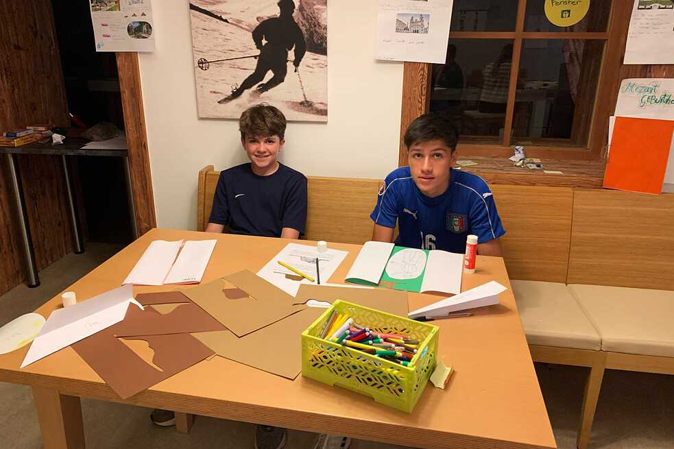 Jugendliche an einem Tisch basteln und malen.