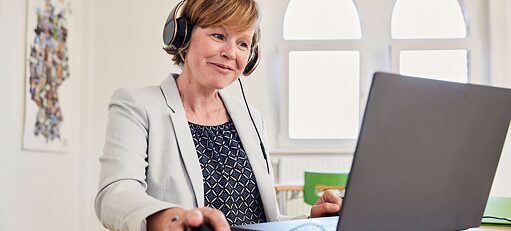 Frau mit Kopfhörern in Online-Meeting