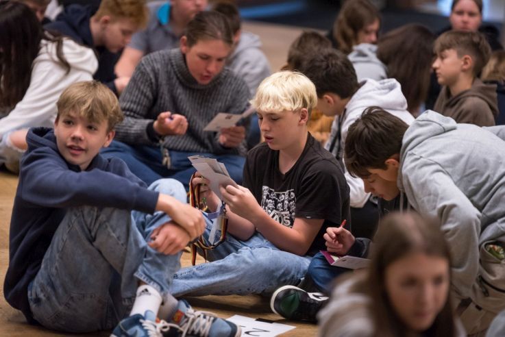 Schüler sitzen im Kreis auf dem Boden.