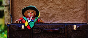 Eine Puppe blickt traurig aus einem alten Koffer.