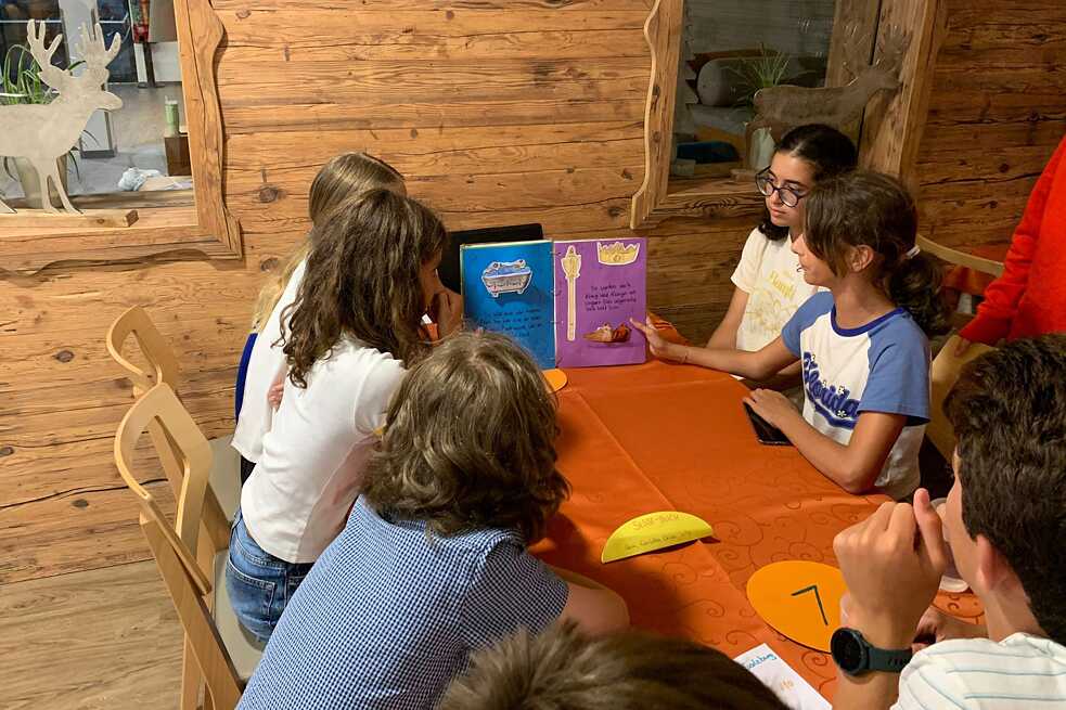 Jugendliche sitzen an einem Tisch und betrachten ein Buch.