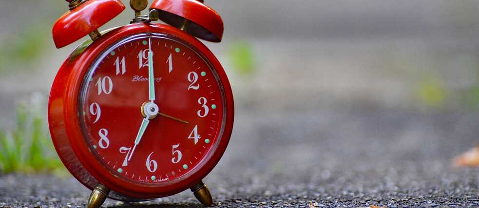 Ein roter Wecker steht auf 7:00 Uhr