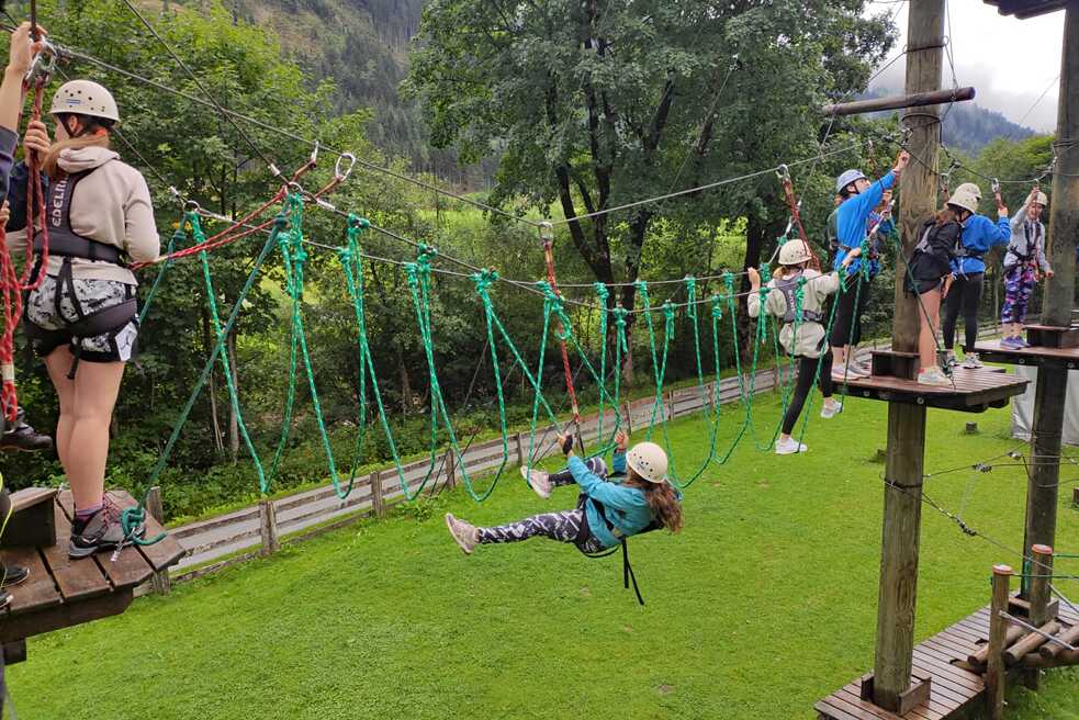 Jugendliche klettern in einem Hochseilgarten.