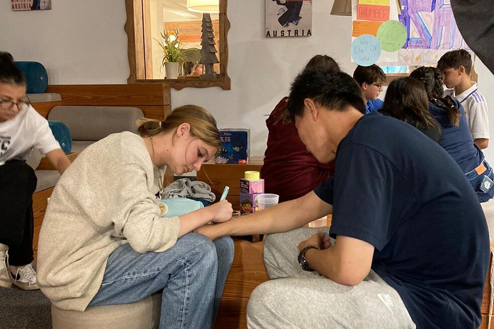 Jugendliche sitzen auf Hockern an einem niedrigen Tisch