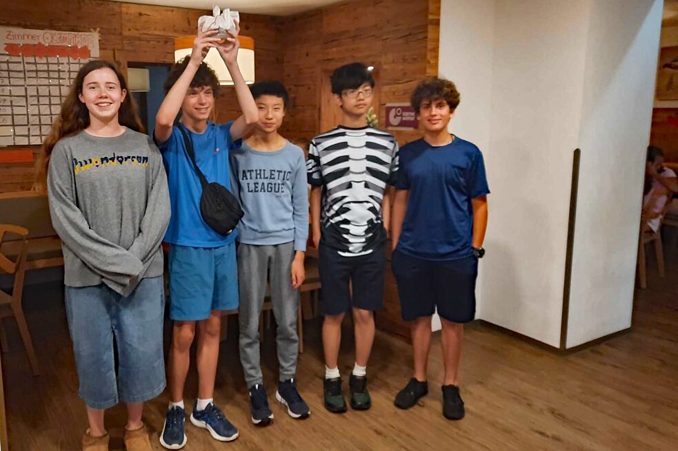 Jugendliche stehen in einer Reihe und halten einen Pokal hoch in die Luft.