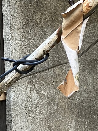 Detailaufnahme, von Kabelstücken umwunden, mit einem Fetzen Markisenstoff