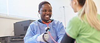 A woman measures another woman's blood pressure. 