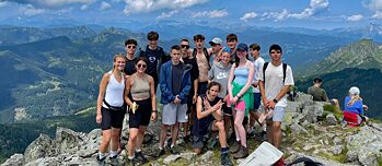 Eine kleine Gruppe Jugendlicher und junger Erwachsener auf einer Bergspitze.