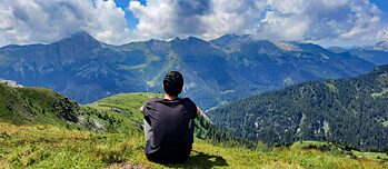 Ein Jugendlicher blickt auf die Berge. Er genießt offenbar die Landschaft.