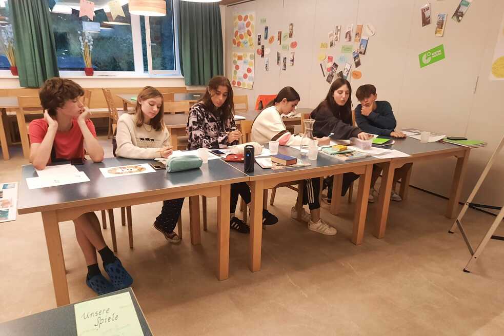 Jugendliche sitzen an Tischen und lernen.