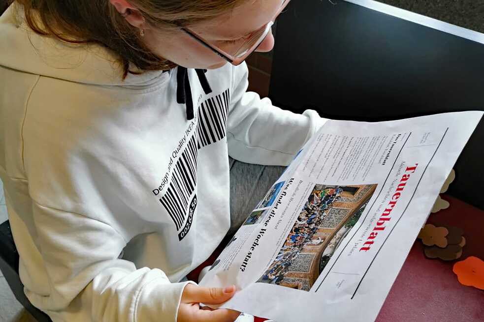 Jugendliche liest eine Zeitung.