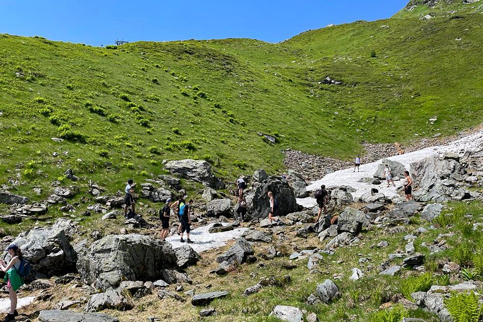 Jugendliche auf einem Bergwanderweb unter strahlend blauem Himmel.