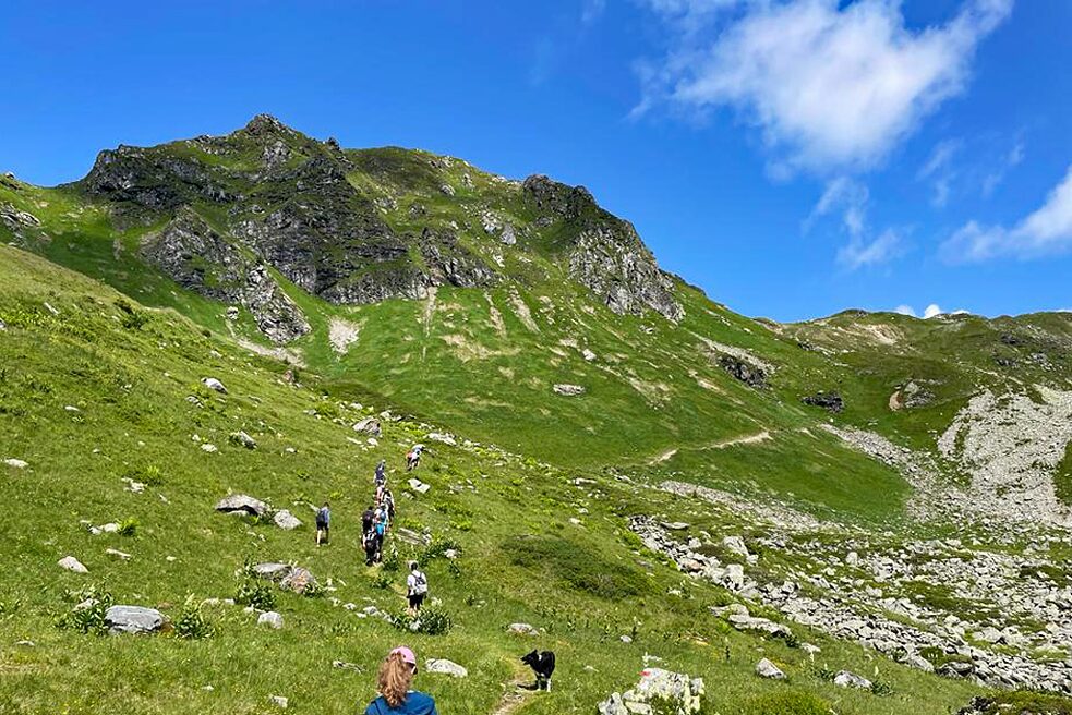 Jugendliche auf einem Bergwanderweb unter strahlend blauem Himmel.