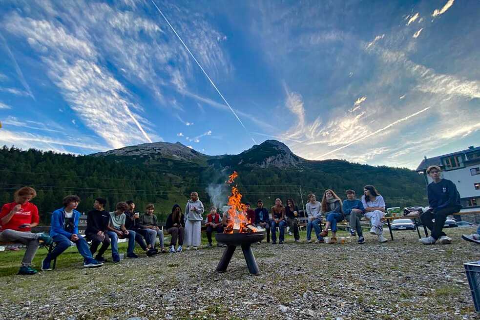 Jugendliche um ein Lagerfeuer.