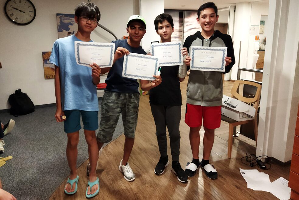 Eine kleine Gruppe Jugendlicher hält stolz Zertifikate in die Kamera.