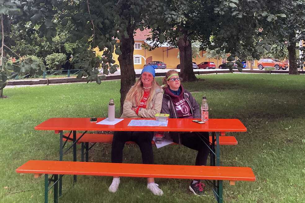 Zwei junge Erwachsene sitzen entspannt auf einer Bierbank.