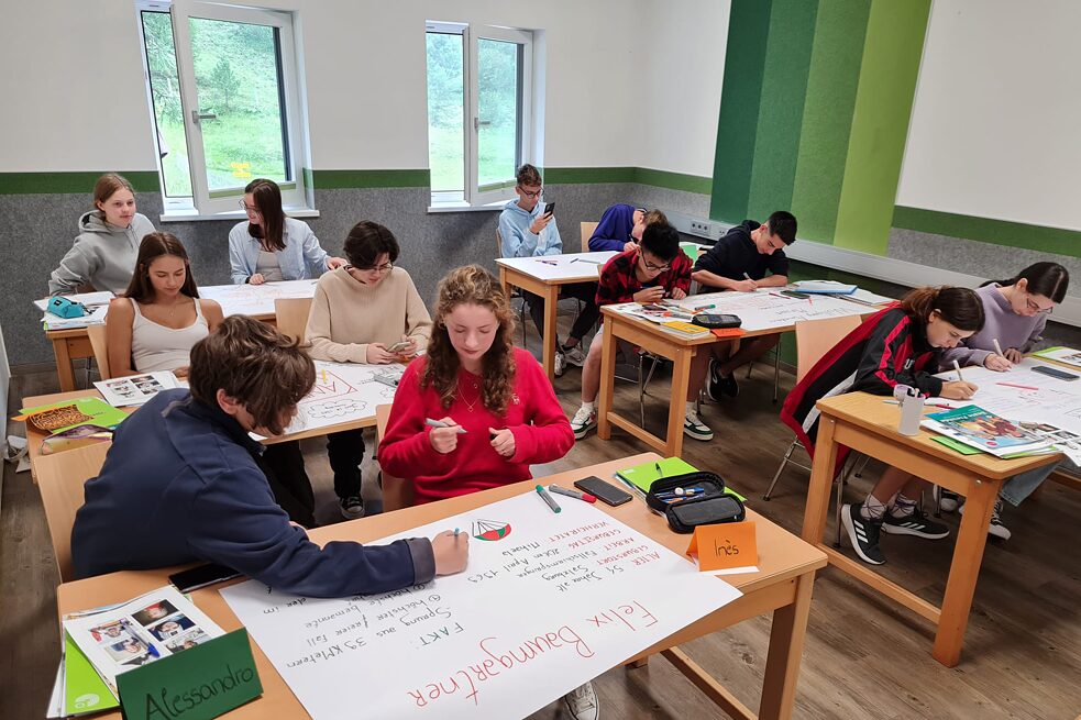 Jugendliche in einem Klassenzimmer arbeiten an Plakaten.