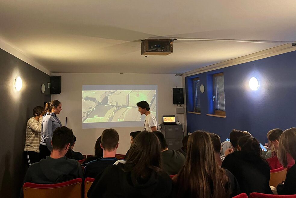 Jugendliche in einen Raum sehen einen an die Wand projizierten Film.