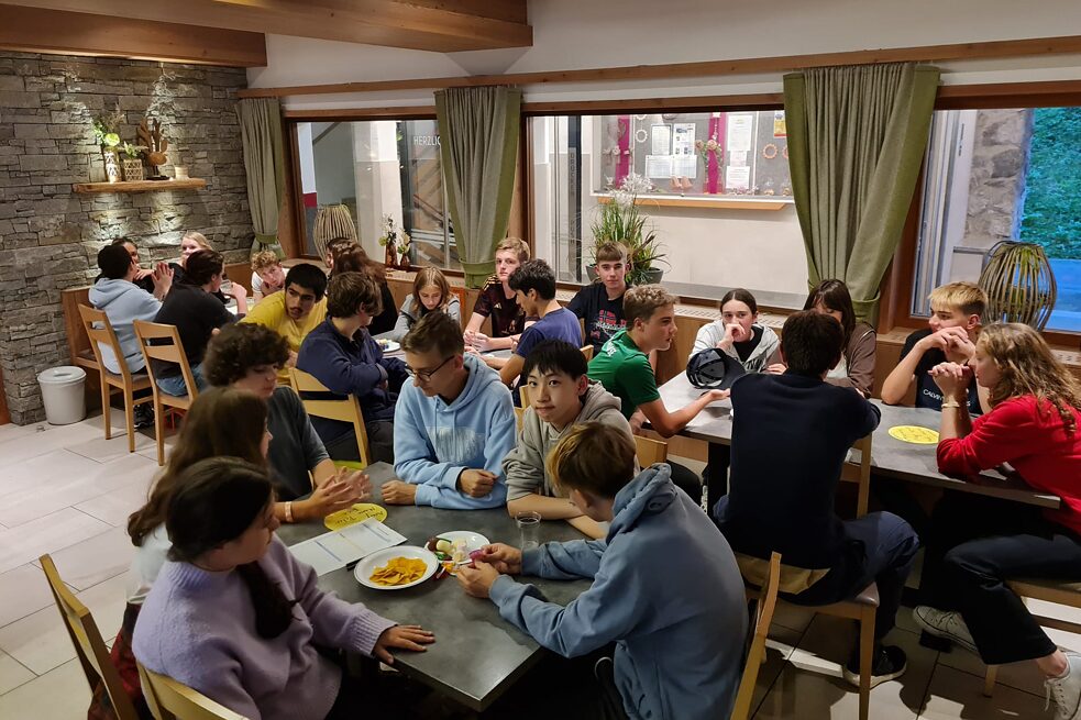 Jugendliche an Tischen wirken konzentriert.