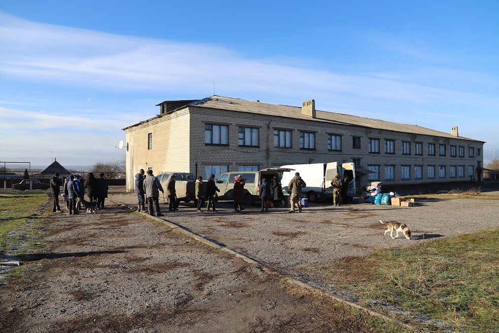 Dezember 2022: Spendenaktion im Dorf Losowe, Oblast Donezk. Seit zehn Monaten hatte die Bevölkerung weder Strom noch Gas. Gasleitungen werden repariert, während in der Ferne Artillerie kracht. Auch das Mobilfunknetz ist oft gestört, es kursierte viel russische Propaganda.