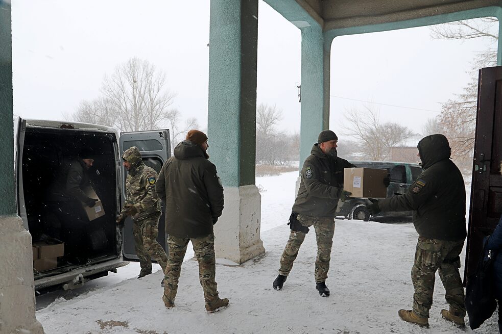 Februar 2022: Spendenaktion in Piski-Radkiwski, Oblast Charkiw − Freiwillige einer Polizei-Einheit im Fronteinsatz helfen beim Kistenschleppen.