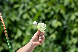 Eine Frau hält einen Federball in die Luft