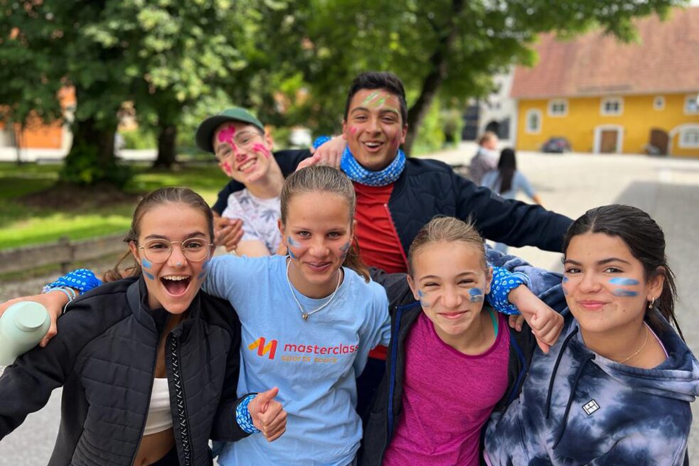 Eine kleine Gruppe Jugendlicher mit bunter „Kriegsbemalung“ im Gesicht lächelt in die Kamera.