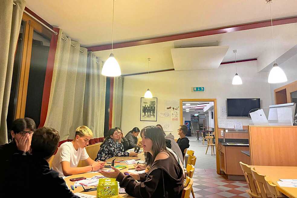 Jugendliche an einem Tisch diskutieren und malen.