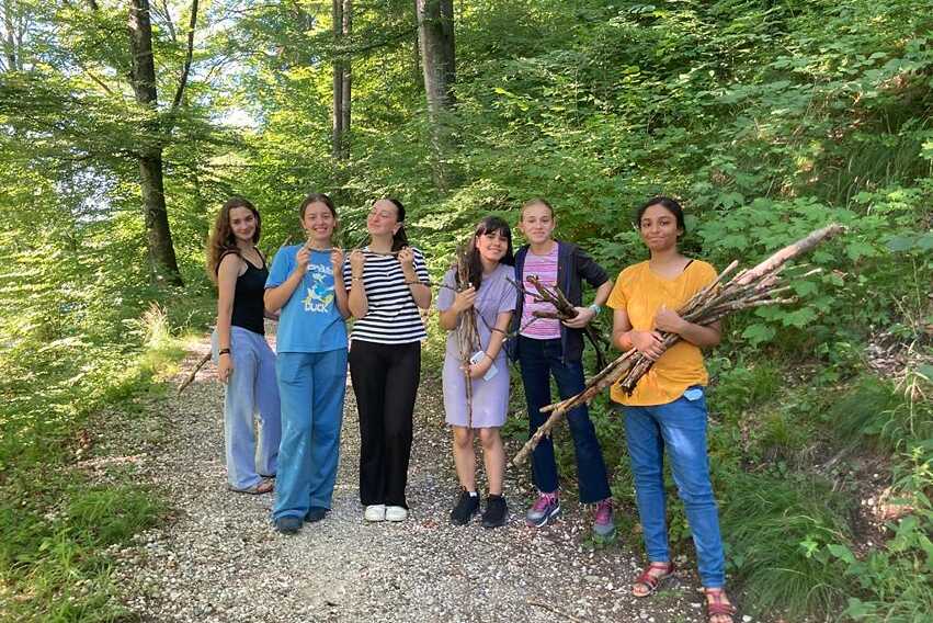 Eine Gruppe Jugendlicher sammelt Stöcke für ein Lagerfeuer im Wald