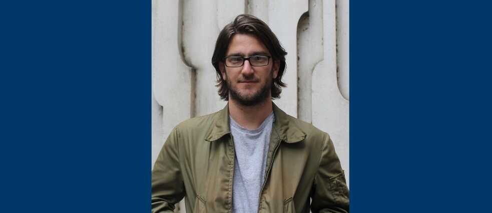 Portrait of Nate Berg on navy blue backdrop 