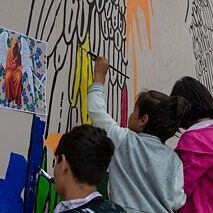 Three children paint on a large canvas where the street art work of the art collective ArtLords is created