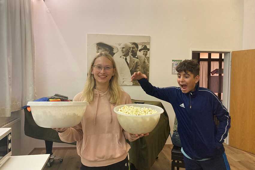Eine junge Frau hält eine Schüssel Popcorn. Ein Junge freut sich darauf.