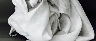 A dancer is wrapped inside a huge roll of material and might be emerging or going into hiding